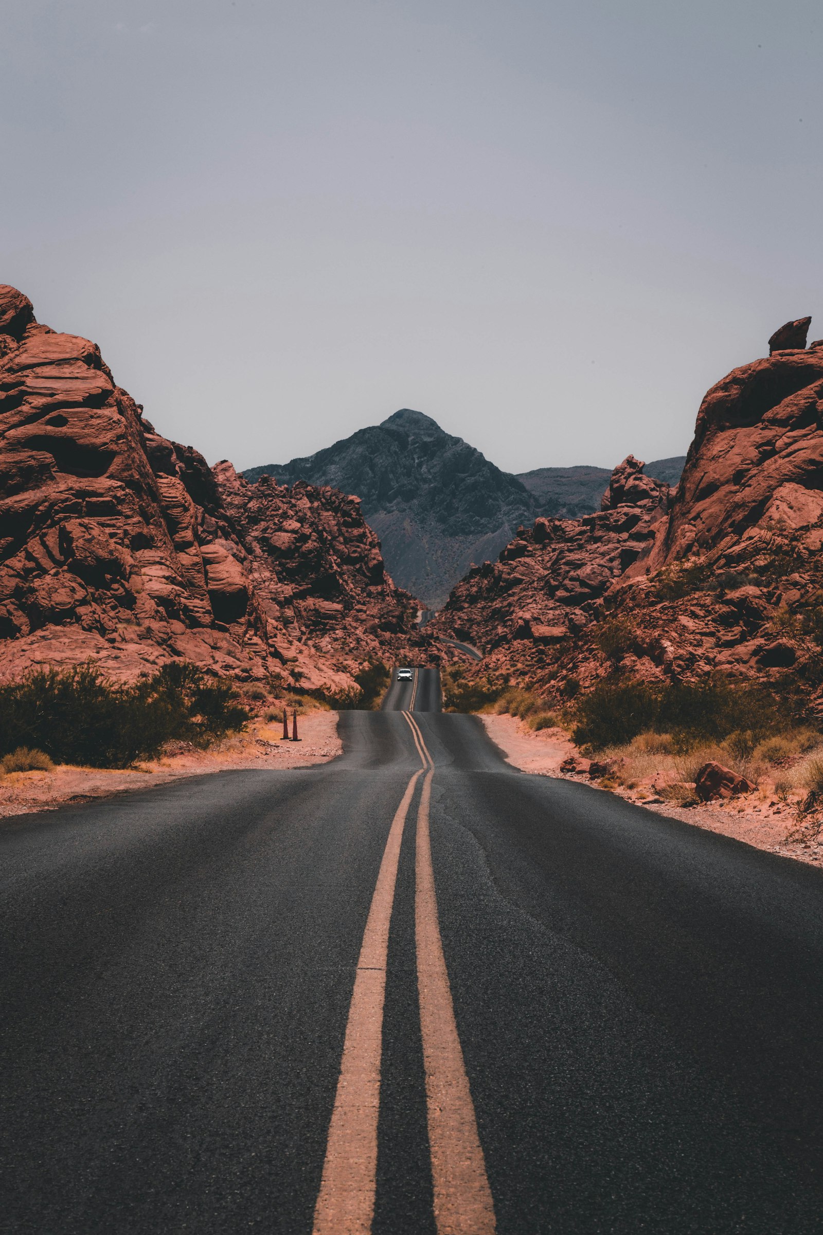 A straight desert road running toward red rock mountains
