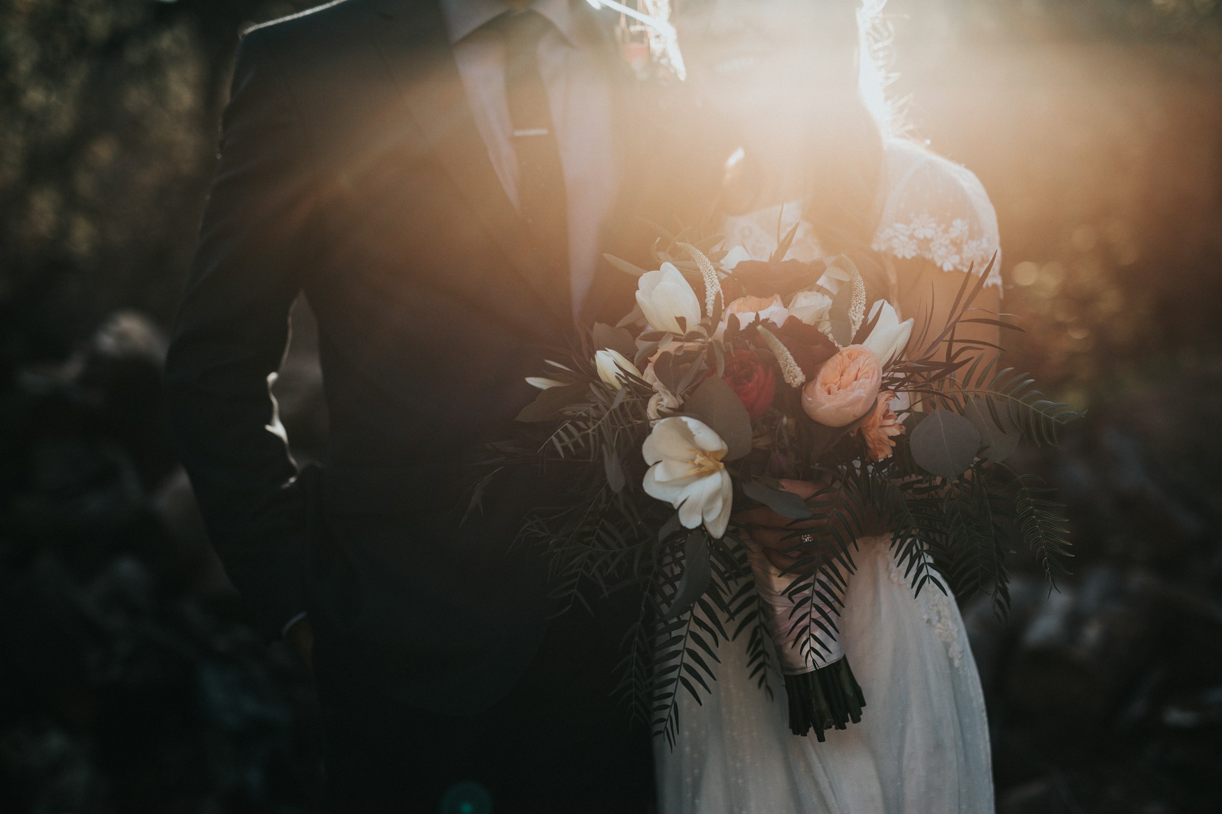 A couple holding a bouquet in warm evening backlight